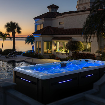 Swim spa in the backyard surrounded by bushes with LEDs lit.